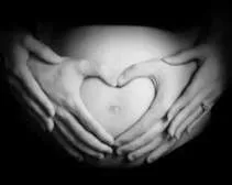 Hands forming a heart around a pregnant belly