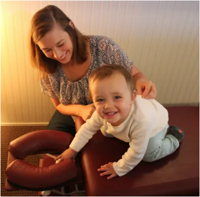 Dr. Amanda gently adjusting a smiling baby at Seaside Chiropractic